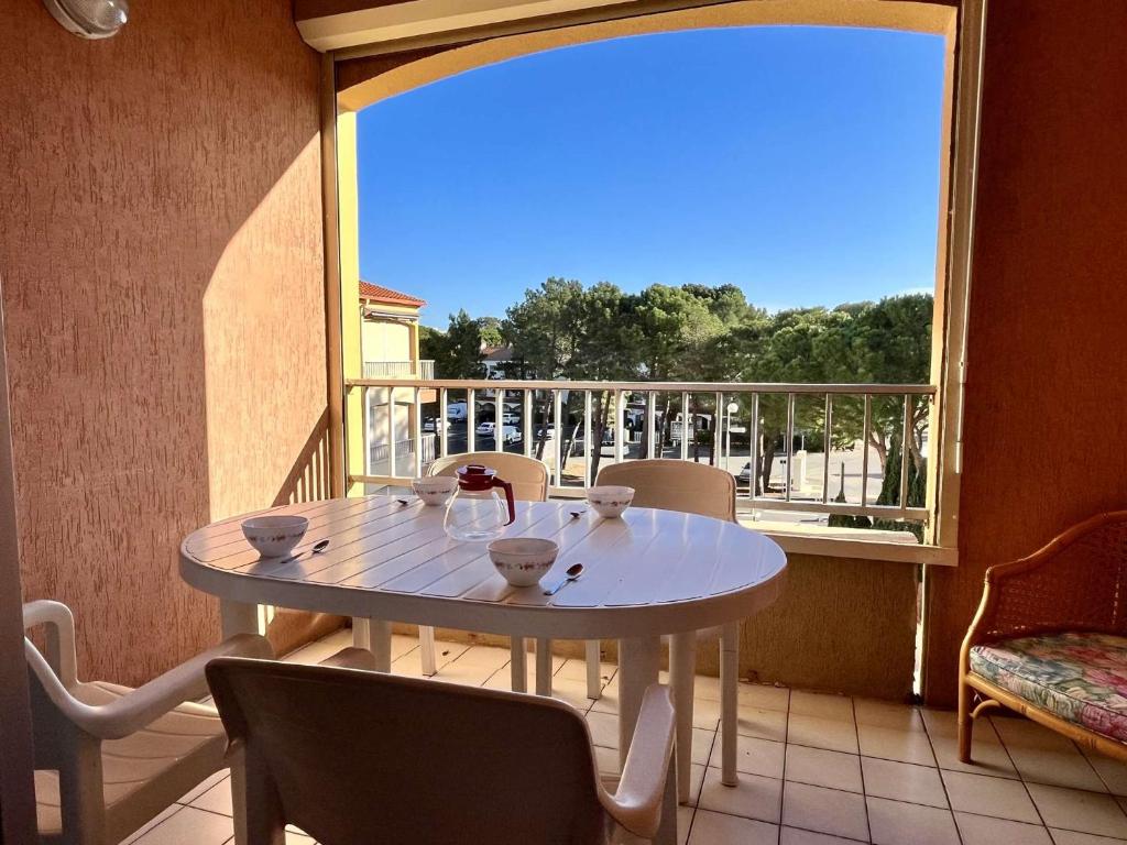 d'une table et de chaises blanches sur un balcon avec fenêtre. dans l'établissement Appartement Studio mezzanine 4 couchages ARGELES SUR MER AR070-149, à Argelès-sur-Mer