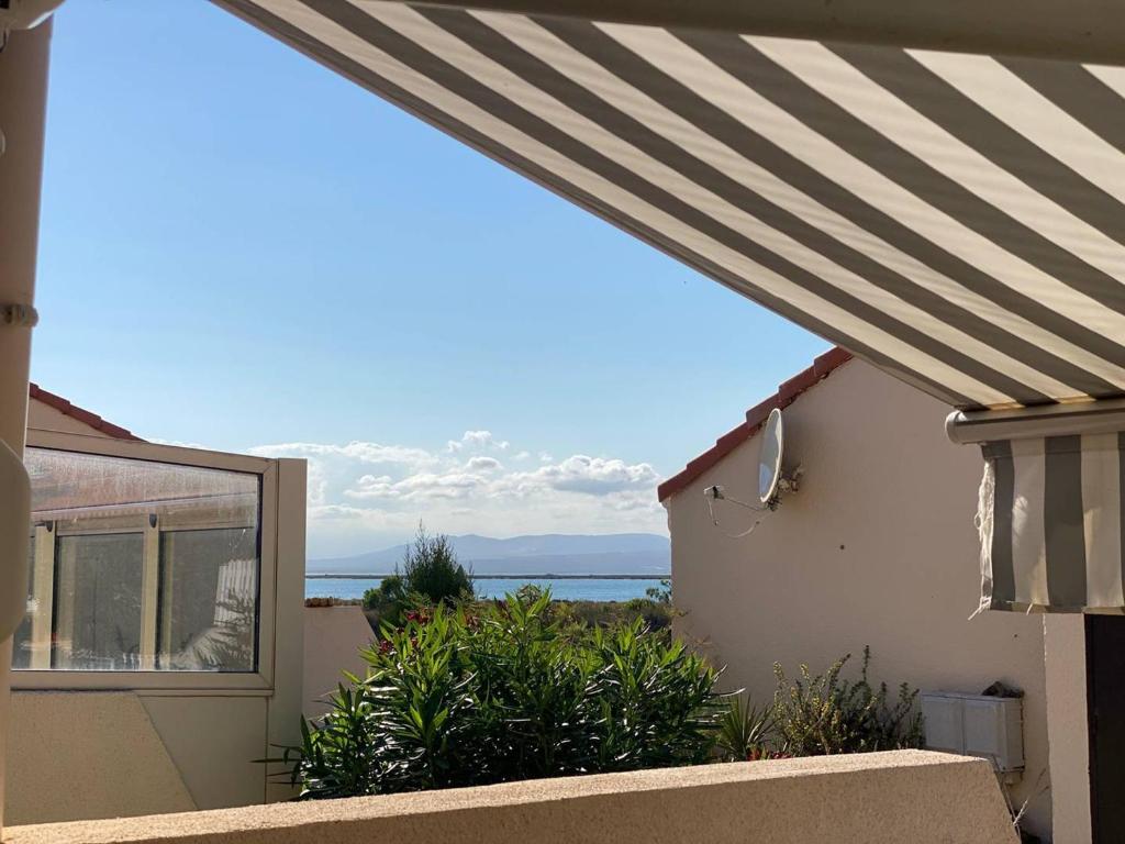 - une vue sur l'océan depuis une maison avec un auvent rayé dans l'établissement Villa cosy 4 pers, terrasse, parking privé à Port Leucate - FR-1-81-628, à Port-Leucate