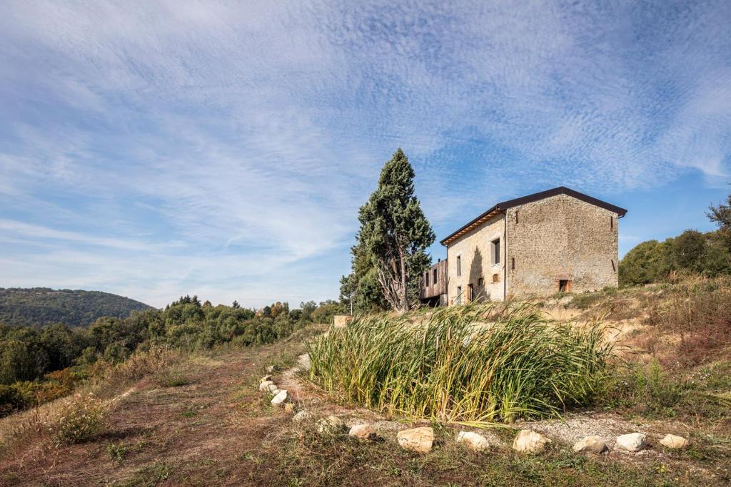 an old building on a hill with a tree at Ca' Inua - arte, bosco, ospitalità in Marzabotto