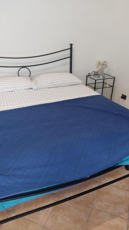 a bed with a blue blanket on top of it at Stanza in Villa in Torvaianica