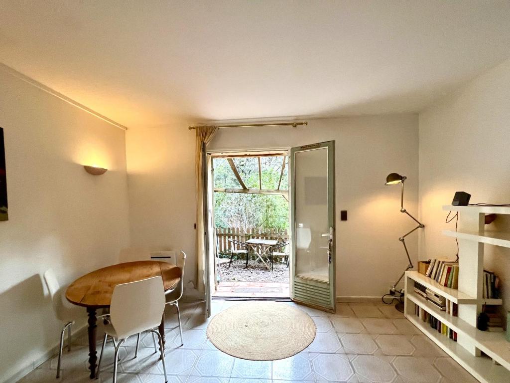 une salle à manger avec une table et une porte menant à une terrasse dans l'établissement Appartement niché dans la verdure, à Aix-en-Provence