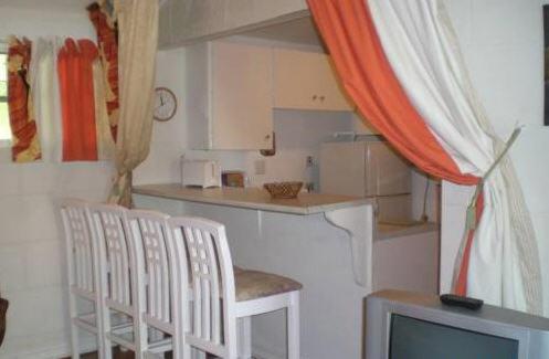 a kitchen with four white chairs and a television at The Legend Garden Condos in Saint Peter