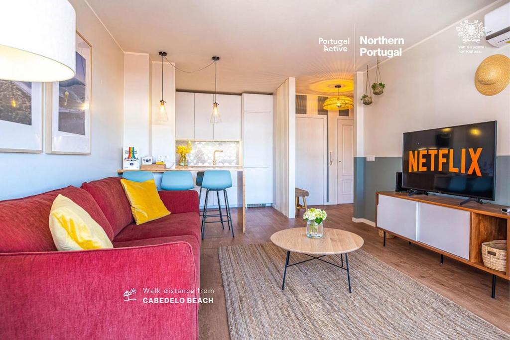 a living room with a red couch and a tv at BlueGreen Beach Apartment in Viana do Castelo