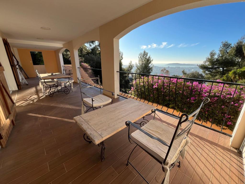 une terrasse couverte avec une table et des chaises en bois sur un balcon dans l'établissement Bas de villa, vue mer, terrasse, clim, piscine, à Toulon