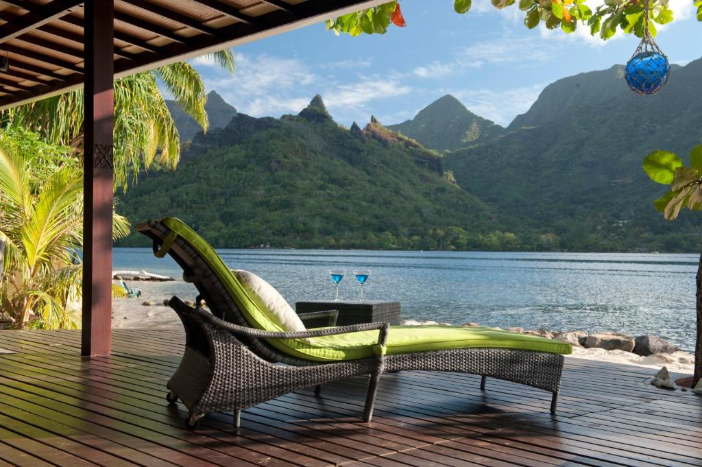 a chair on a deck with a view of a lake at Robinson's Cove Villas - Deluxe Wallis Villa in Papetoai