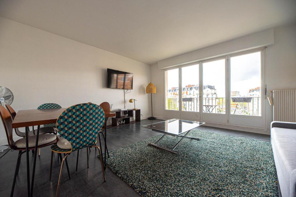 - un salon avec une table, des chaises et une grande fenêtre dans l'établissement CIA - Pereire, Spacious Flat with Balcony, à Paris