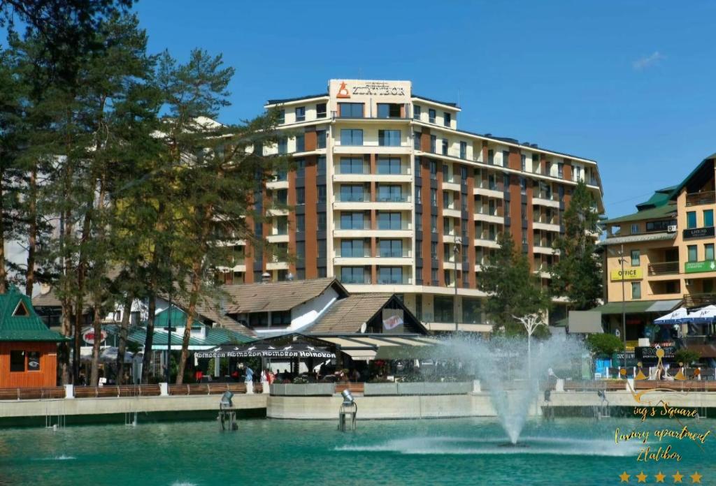 a fountain in the water in front of a building at King's Square Lux apartment Zlatibor 2 in Zlatibor