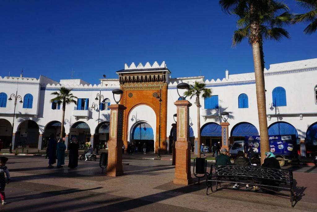 a building with a gate and palm trees in a plaza at Dar lara in Larache