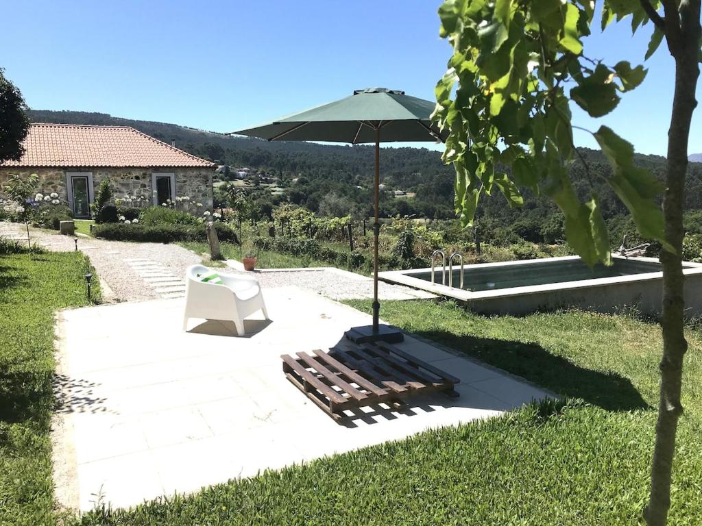 a patio with a bench and an umbrella at Casa do Paço in Paredes de Coura