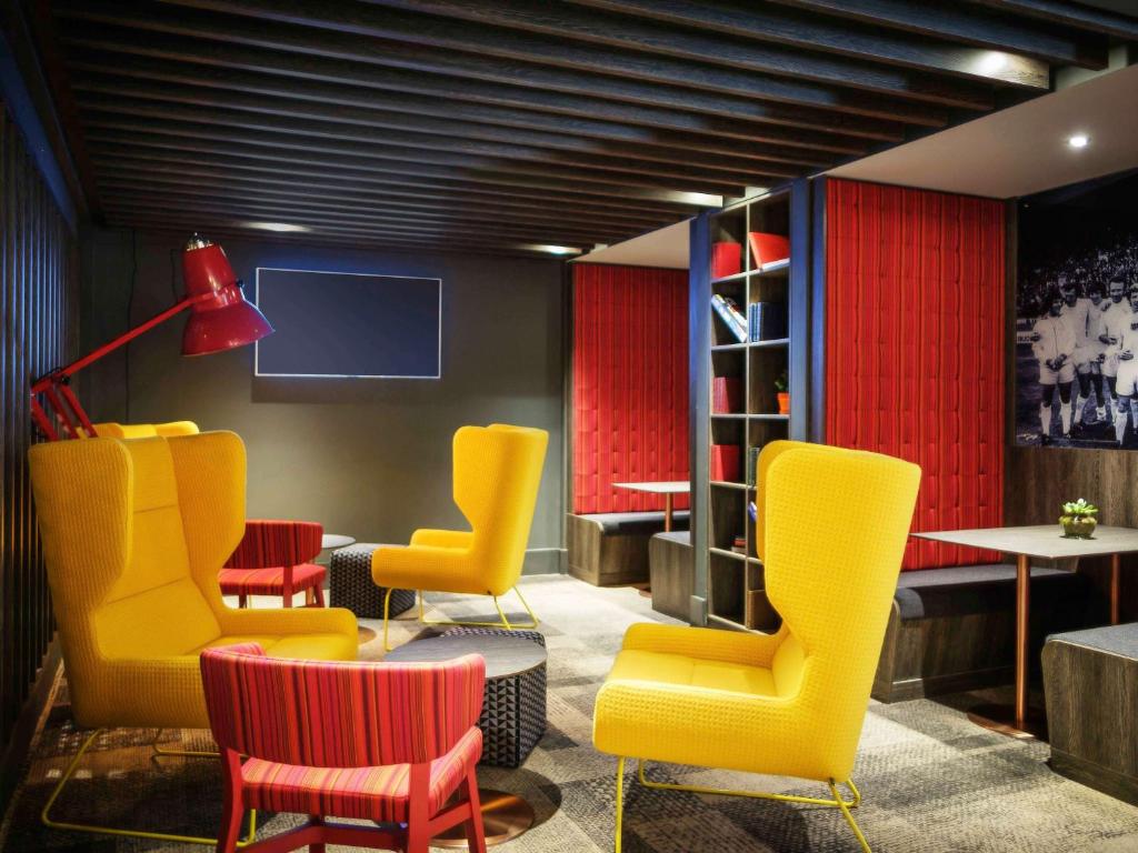 a waiting room with yellow chairs and a tv at ibis Styles Leeds City Centre Arena in Leeds