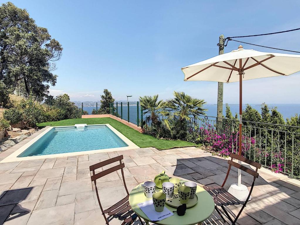 une terrasse avec une table, un parasol et une piscine dans l'établissement Sur les hauteurs de Théoule villa avec une magnifique vue mer, à Théoule-sur-Mer