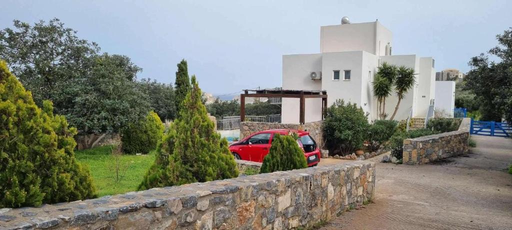 a red car parked in front of a house at Plaka-Sleeps4-Parking-Pool-HotTub-SeaViews in Elounda