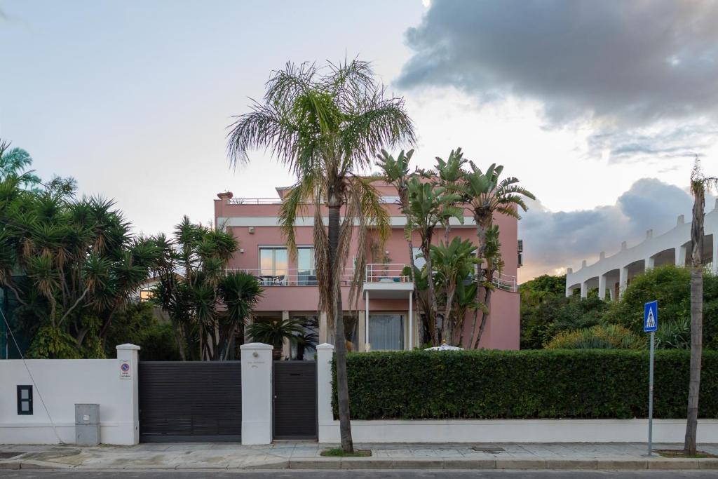 a pink building with palm trees in front of it at Villa Olimpia in Mondello