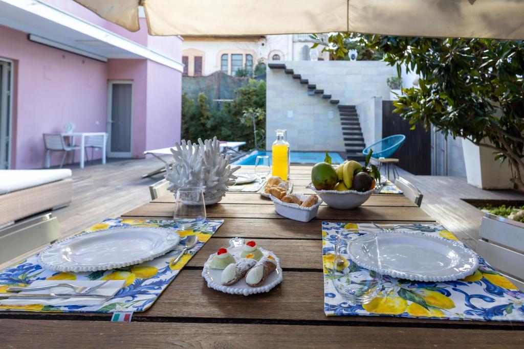 a wooden table with plates and food on it at Villa Olimpia in Mondello