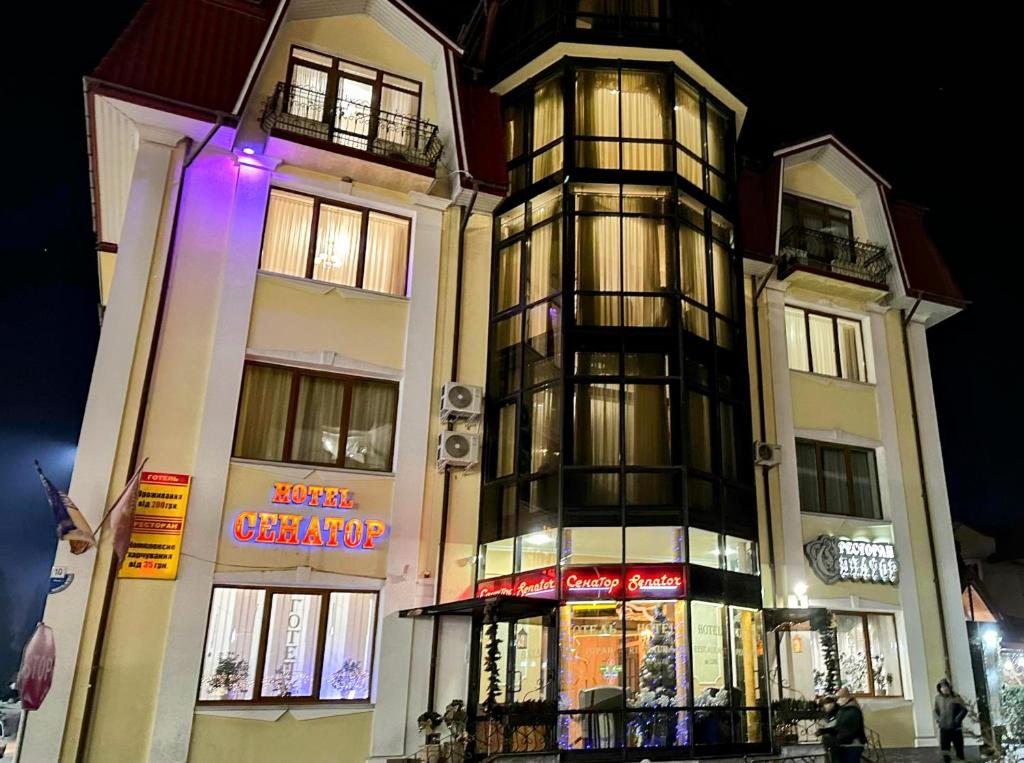 a tall building with a sign on the side of it at Hotel&Restaurant SENATOR in Truskavets