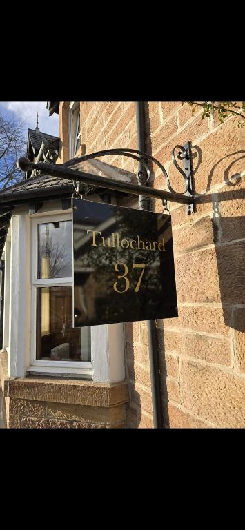 a sign on the side of a building with a window at Tullochard Guest House in Alness