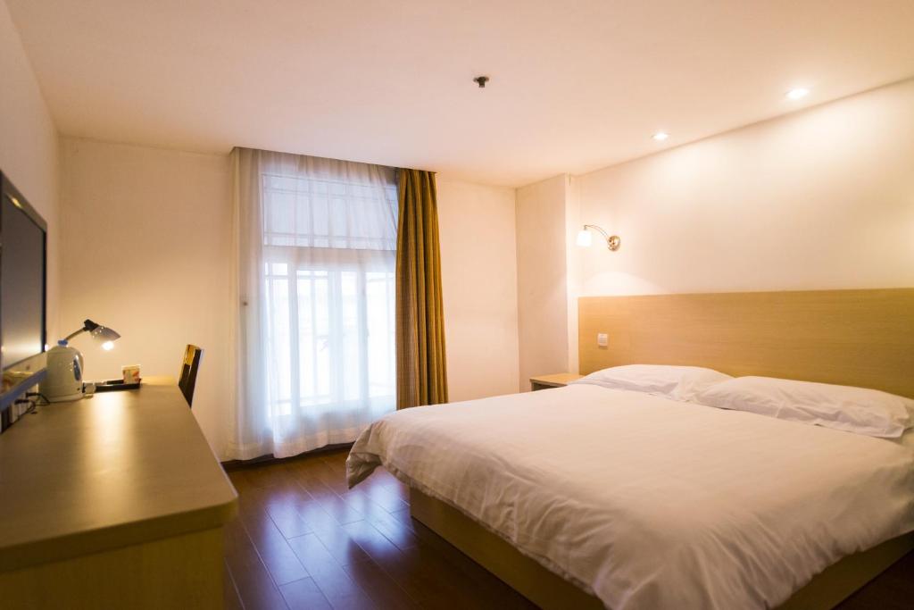 a hotel room with a bed and a window at Motel Shanghai Pudong Lianyang New International Expo Centre in Shanghai