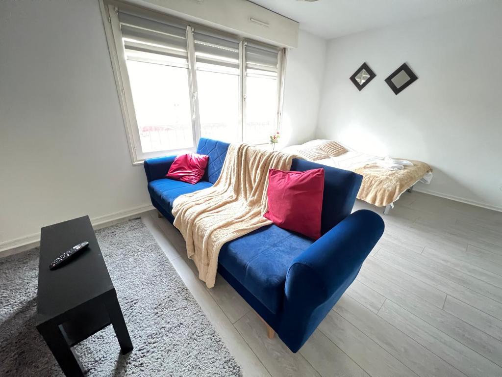 a living room with a blue couch with red pillows at Saint Exupery Parking Wifi Un Séjour à Part in Thionville