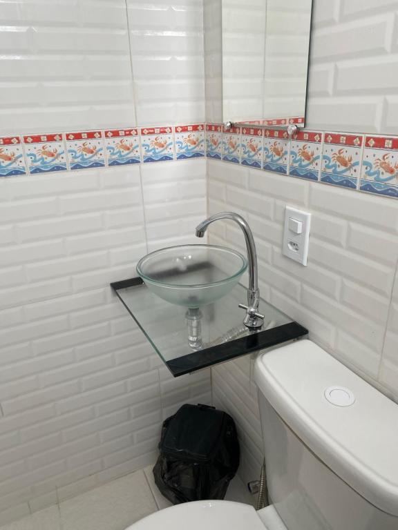 a bathroom with a glass bowl sink over a toilet at Antonia Hospedaria 3 in Búzios