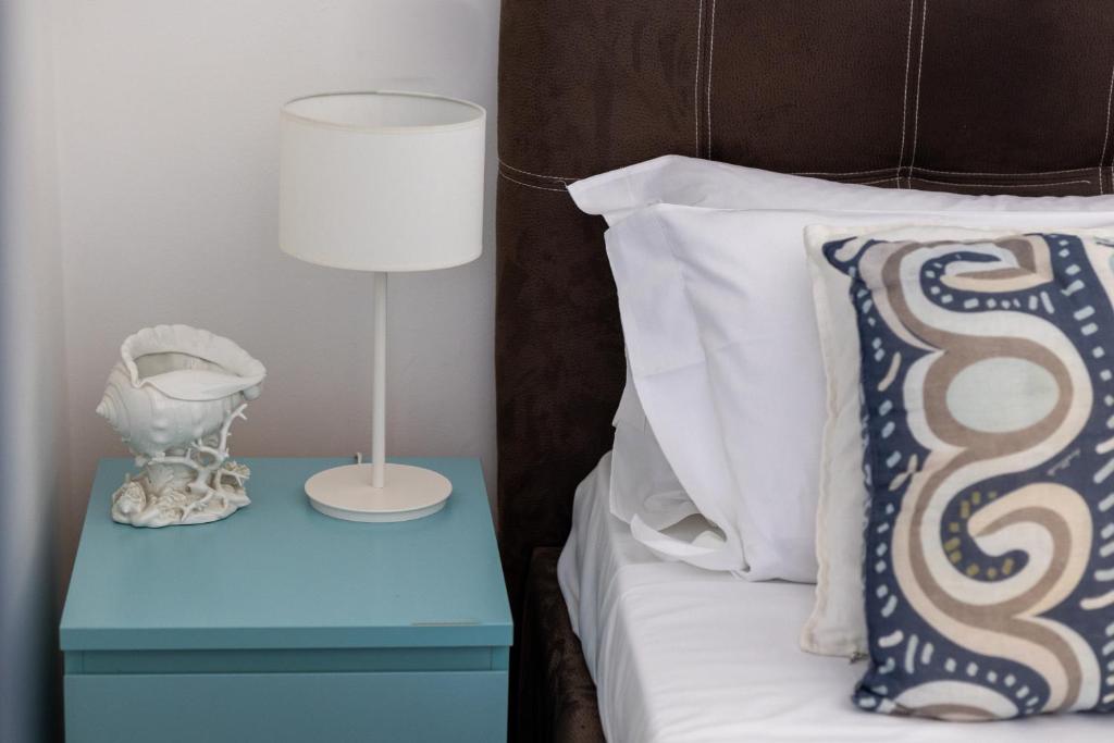 a bed with a blue nightstand with a lamp and a pillow at Villa Olimpia in Mondello