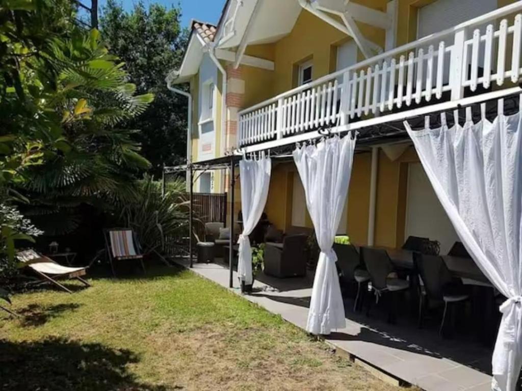une maison avec des rideaux blancs dans la cour dans l'établissement Le Clos d'Alice, à La Teste-de-Buch