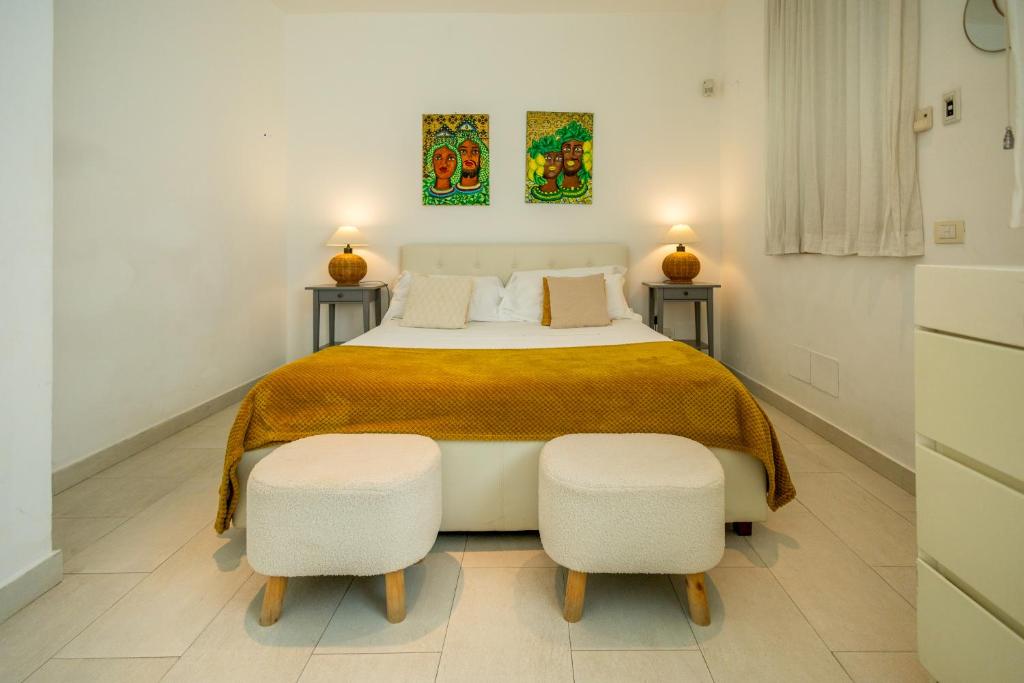 a white bedroom with a large bed with two stools at Villa Olimpia in Mondello