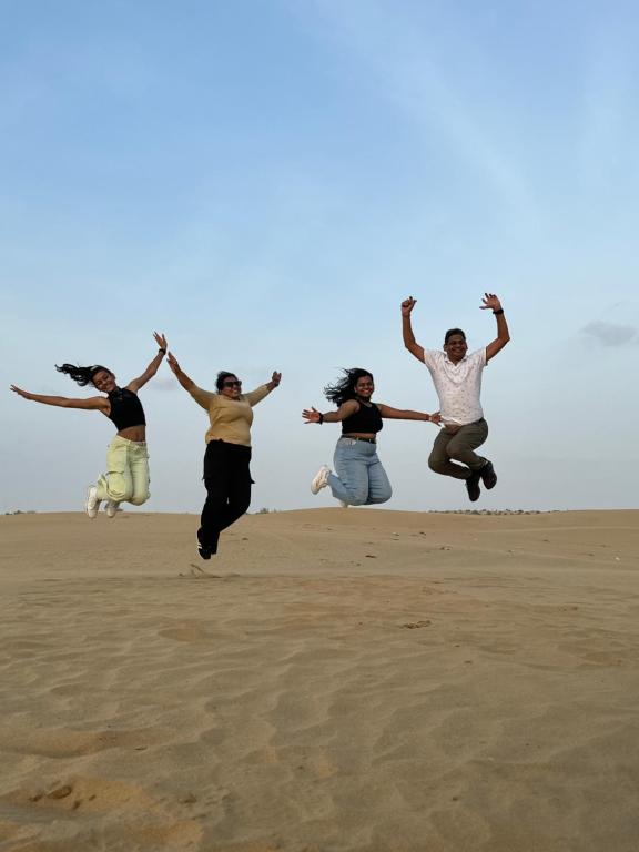 a group of people jumping in the sand at Happy Trails Jaisalmer in Jaisalmer