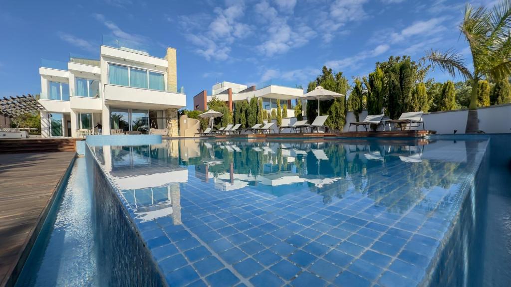 a swimming pool with chairs and a house at Vivo Mare Beachfront Villas - Seashell in Ayia Napa