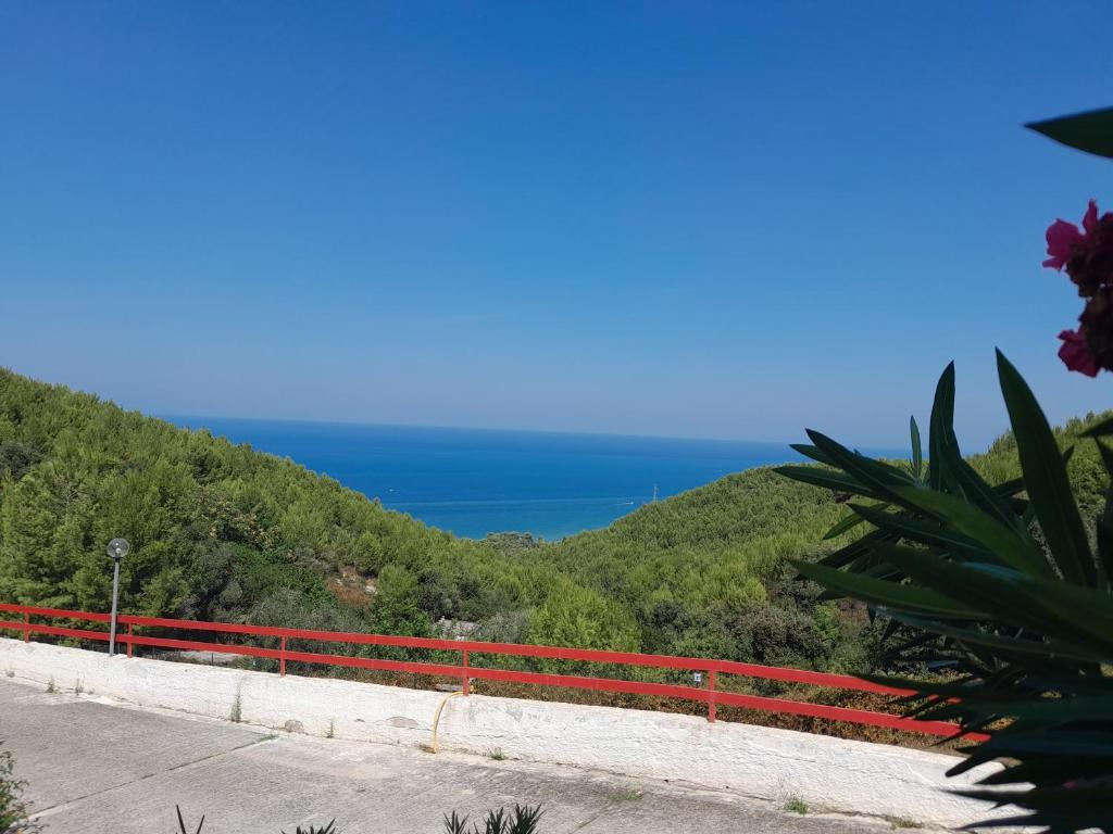 ein roter Zaun auf einem Hügel mit dem Meer im Hintergrund in der Unterkunft La casa di Arianna in Peschici