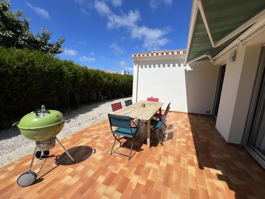 a patio with a grill and a table and chairs at Les Saules in Saint-Gilles-Croix-de-Vie