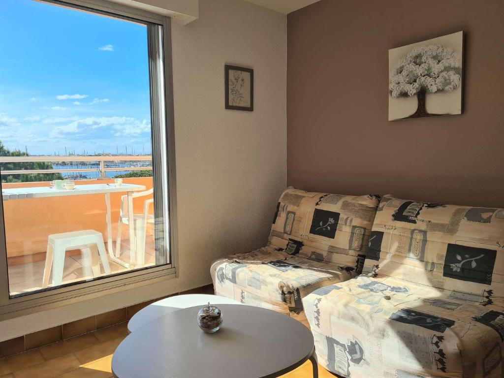 un salon avec un canapé, une table et une fenêtre dans l'établissement Appartement 2 pièces CAP D 'AGDE CT150-G506, au Cap d'Agde