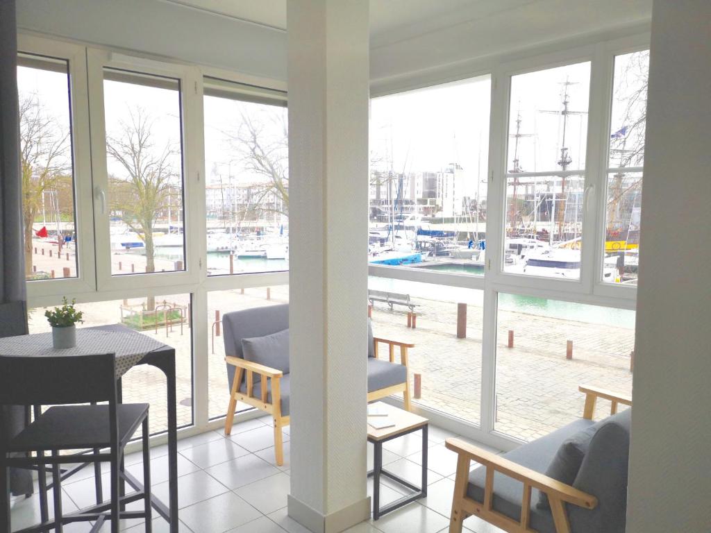 - un salon avec des fenêtres, une table et des chaises dans l'établissement Très bel appartement avec vue d'exception & parking, à La Rochelle