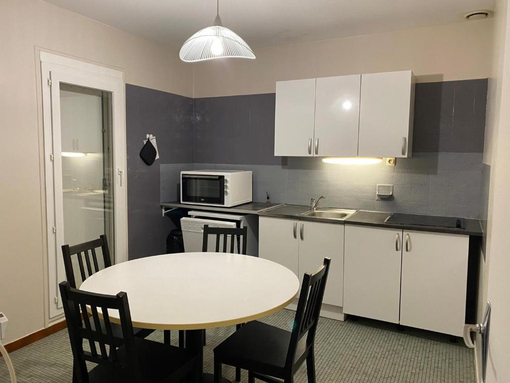 a small kitchen with a table and a microwave at Les Fauvettes in Ouzouer-sur-Loire