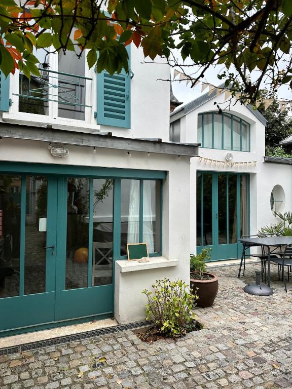 a house with blue doors and a patio at Petite maison calme dans un jardin in Bois-Colombes