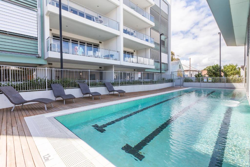 a swimming pool with chairs and a building at Gallery Serviced Apartments in Fremantle