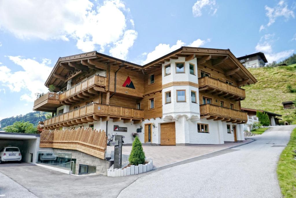 ein großes Holzhaus mit Balkon auf einer Straße in der Unterkunft Studio Niederseer by we rent, JOKERCARD INCLUDED in Saalbach-Hinterglemm