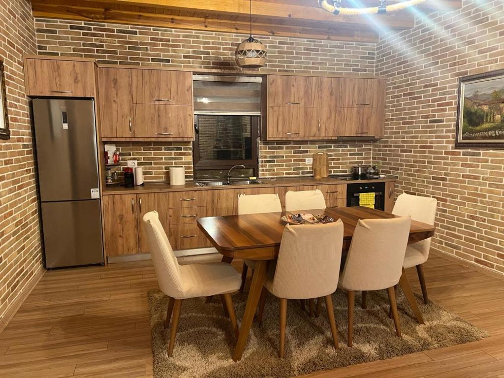 a kitchen with a wooden table and white chairs at Saselisht Harmony 4 Bedroom Villa in Pogradec