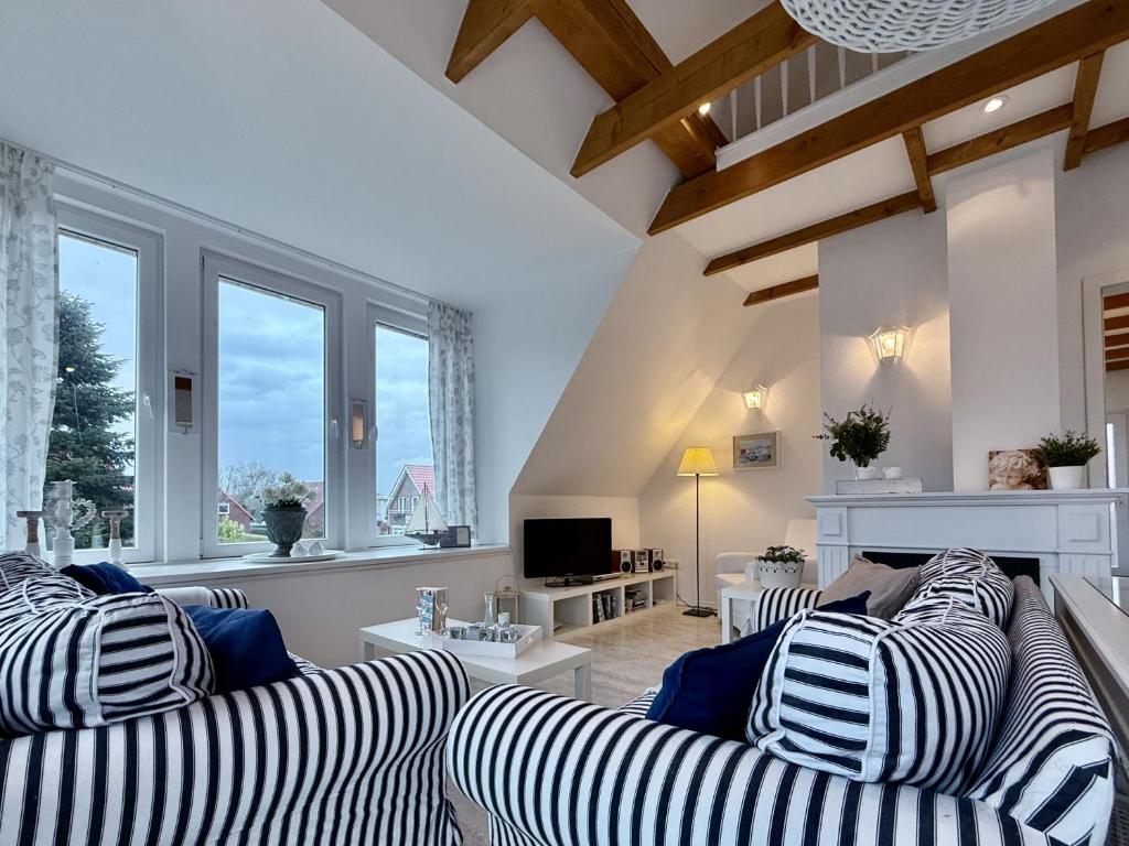 ein Wohnzimmer mit 2 gestreiften Sofas und einem TV in der Unterkunft FeWo Harleglück - Carolinensiel in Wittmund