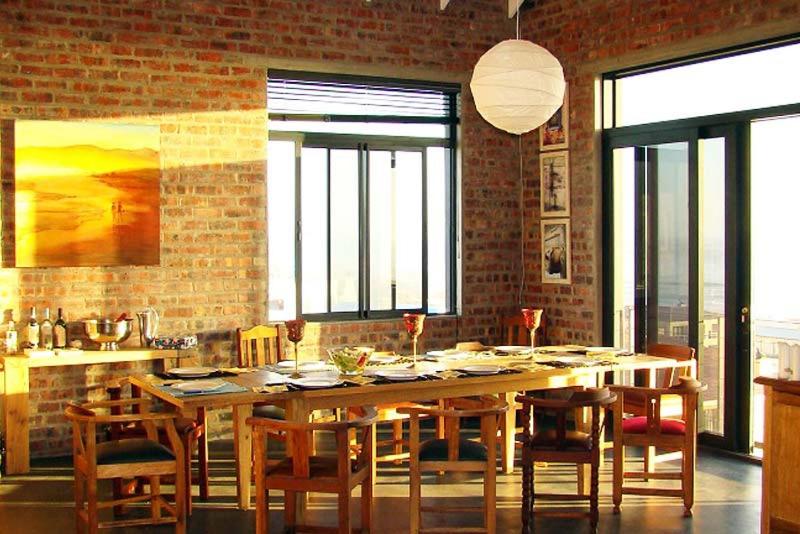 Un comedor con una gran mesa y sillas de madera. en Bella Capensis, en Yzerfontein