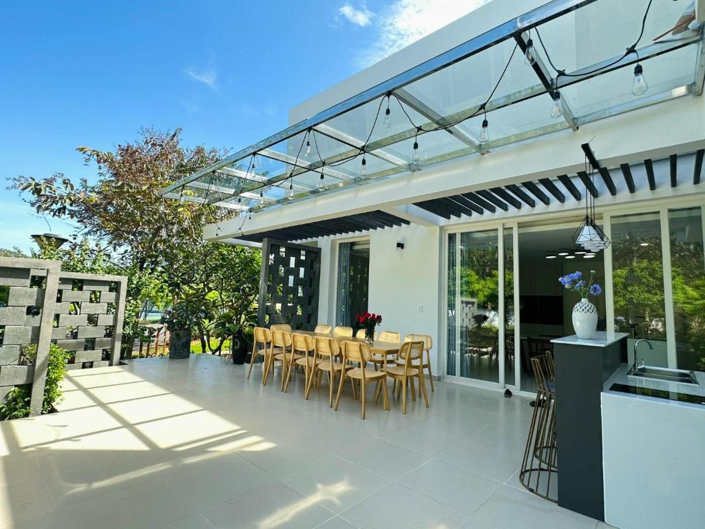 einen Wintergarten mit einem Tisch und Stühlen auf einer Terrasse in der Unterkunft Villa 4pn Oceanami Resort Long Hải Phước Hải in Long Hải