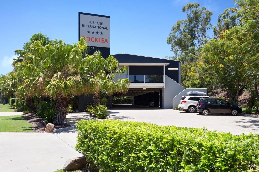a building with cars parked in a parking lot at Rocklea International Motel in Brisbane