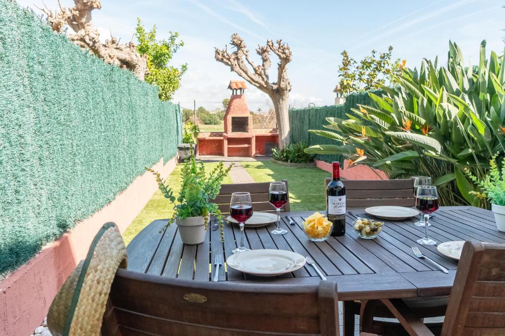 a wooden table with glasses of wine on a patio at Acogedora casa cerca de la playa in Torredembarra