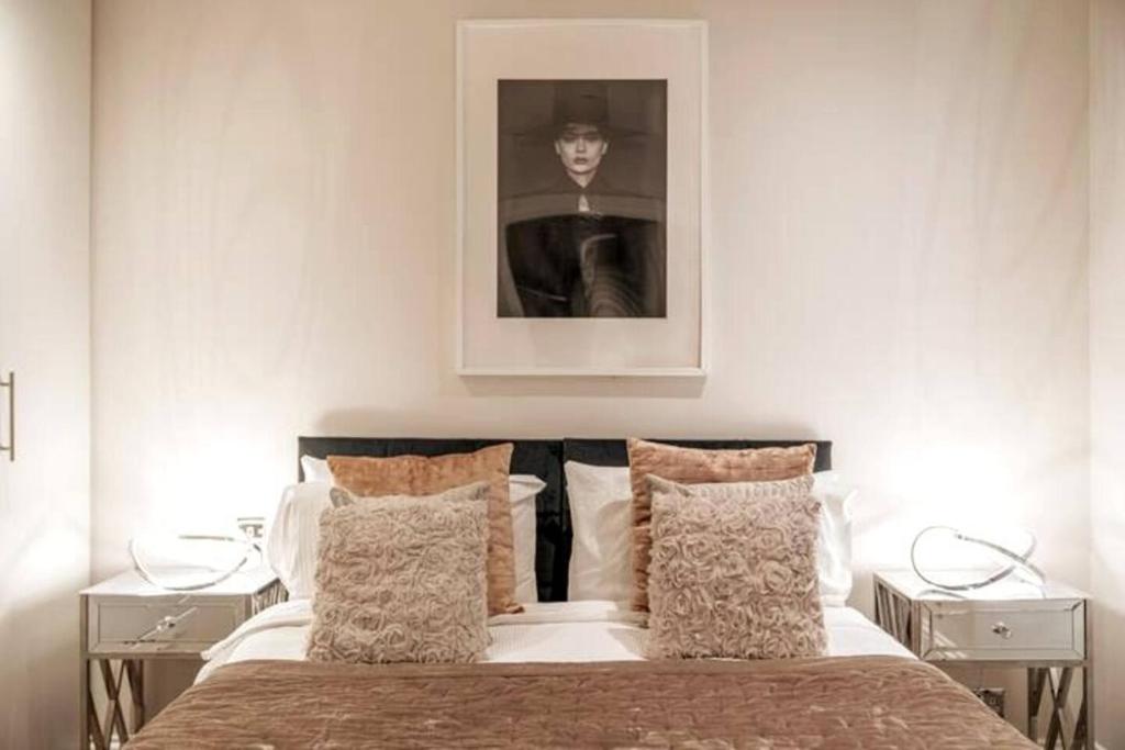 a bedroom with a bed with a picture on the wall at Niru Experience Jewel Of Ifield Road in London