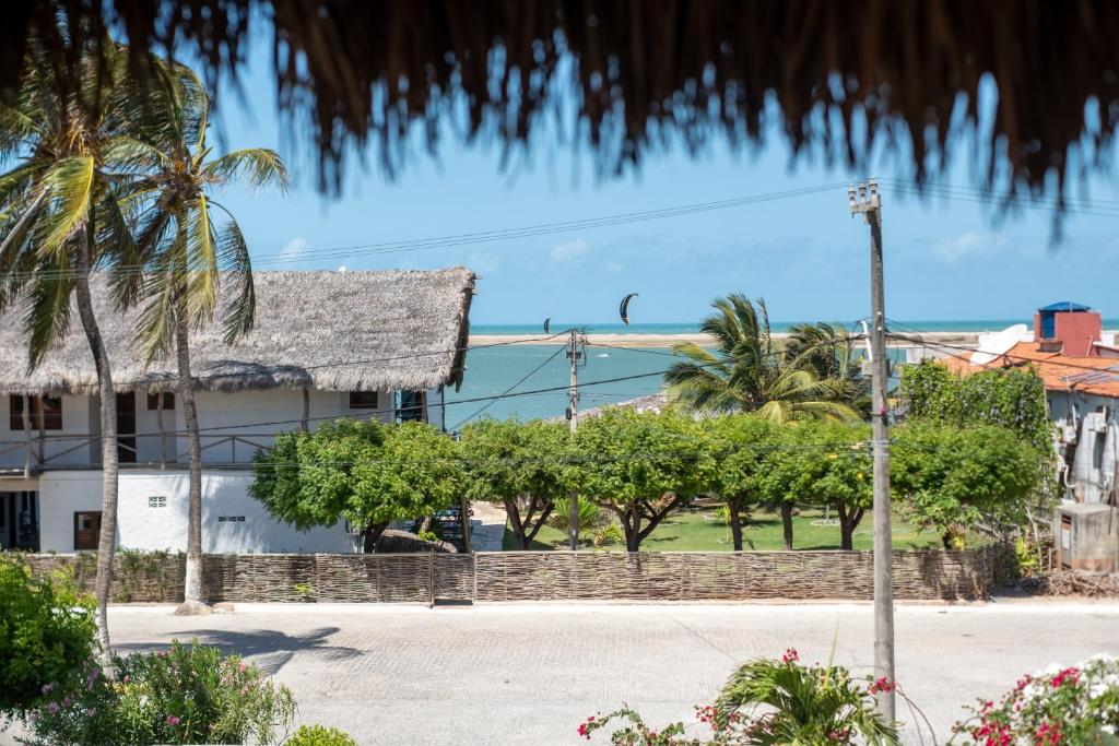 a house with a palm tree in front of a street at Garden House - Ilha do Guajiru in Itarema