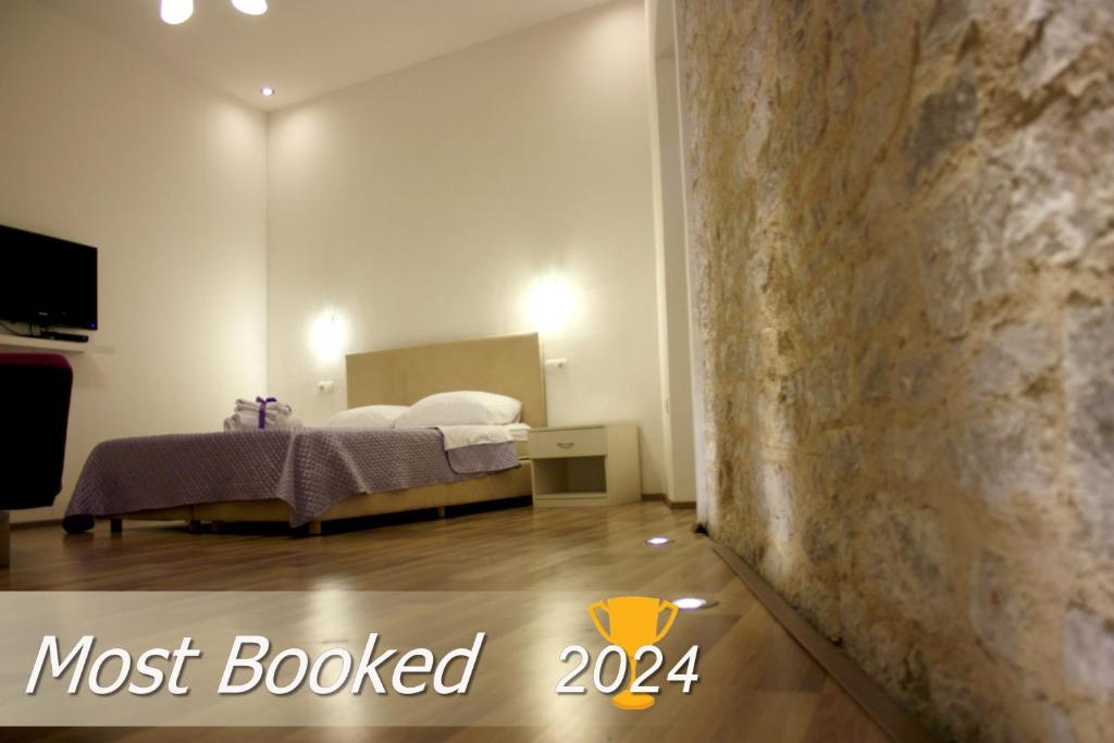 een slaapkamer met een bed en een stenen muur bij Medulić Palace Rooms & Apartments in Šibenik