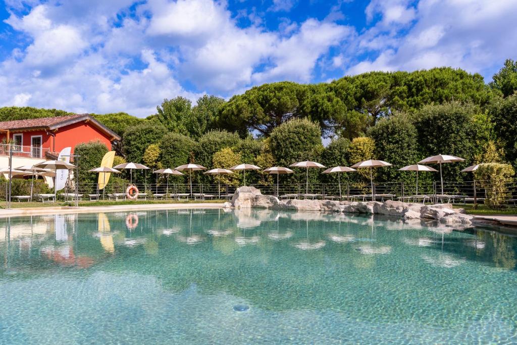 a pool of water with umbrellas in front of a building at Club del Sole Viareggio Family Collection in Torre del Lago Puccini