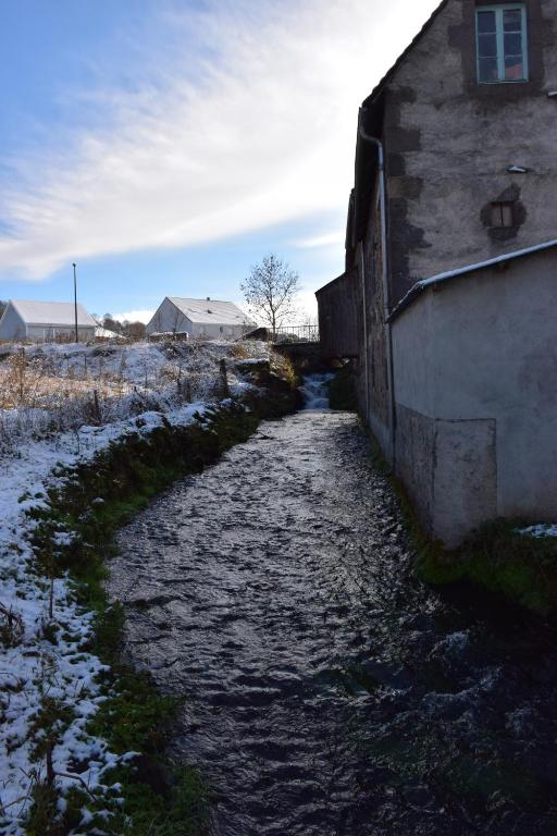 un ruisseau à côté d'un bâtiment avec de la neige au sol dans l'établissement Chez Boucharet, à Ceyssat