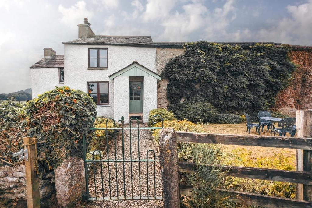 a white house with a fence in front of it at The Gilpin Farmhouse, Lake District Getaway in Levens
