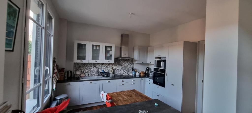 une cuisine avec des armoires blanches et une table à l'intérieur dans l'établissement Maison Saint Pavin, au Mans