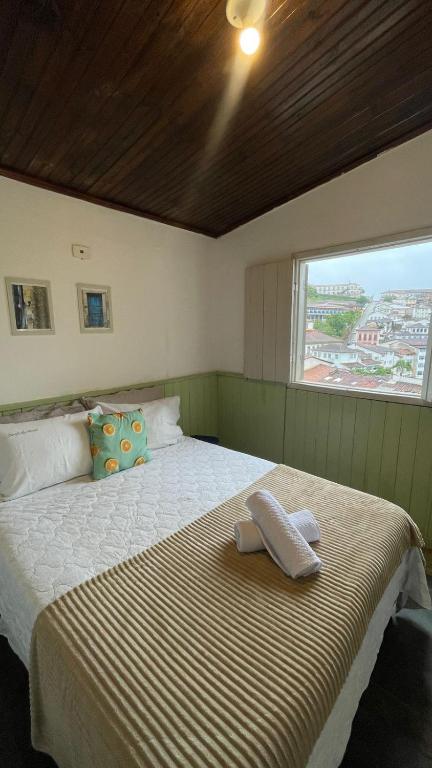 a bedroom with a large bed with a window at Casa Jabuticabeira in Ouro Preto